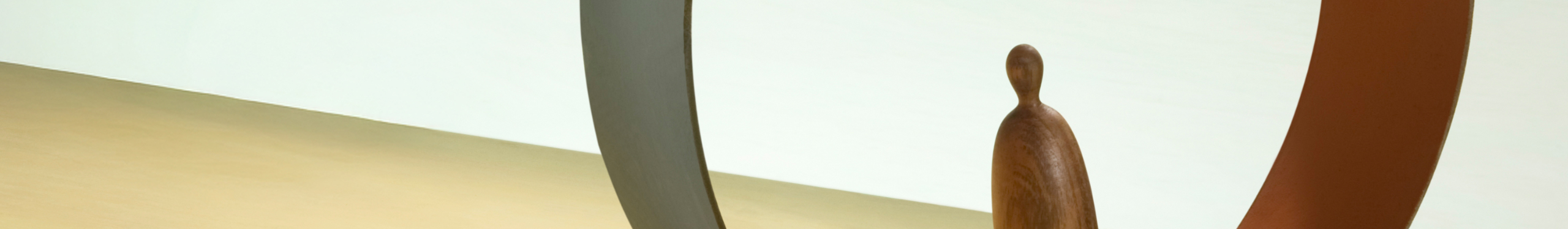 Eine Person in einem Anzug hält ein Surfbrett am Strand. Der Hintergrund zeigt verschwommenes Meer und Himmel in sanften Blautönen. Das Bild kombiniert formelle Kleidung mit einem Freizeitobjekt, was einen Kontrast zwischen Arbeit und Freizeit darstellt.