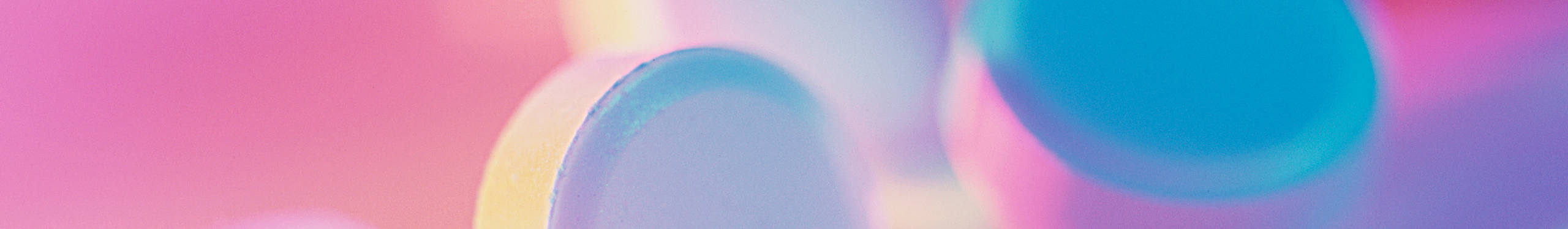 Ein abstraktes Foto mit weichen, verschwommenen Formen in Pastellfarben. Die Farben verlaufen von Rosa über Lila bis hin zu Blau und erzeugen einen sanften, beruhigenden Effekt. Die Formen sind rund und scheinen sich zu überlappen, was dem Bild eine dreidimensionale Tiefe verleiht.