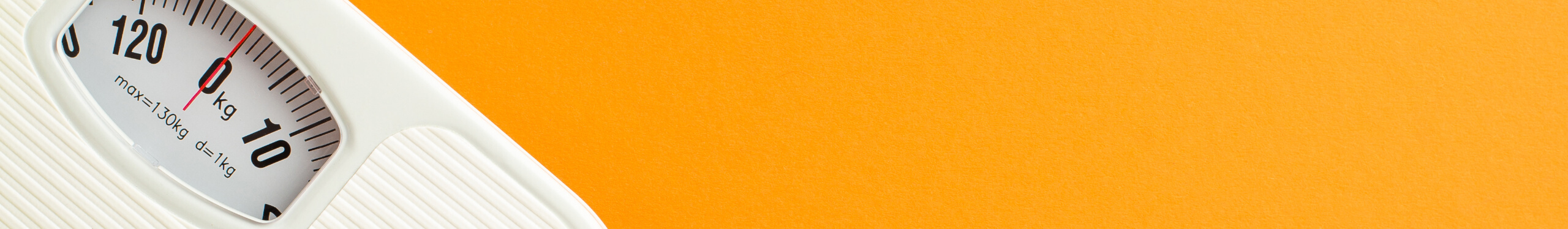 Eine weiße Personenwaage auf einem orangefarbenen Hintergrund. Die Skala zeigt knapp über 0 kg an, mit einer maximalen Kapazität von 130 kg.